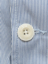 Close-up of a white button with Blue de Gênes text on a blue and white stripe cotton fabric, featuring visible stitching, indicative of the Gabbiano Riga Blazer - Blue Stripe by Blue de Gênes.