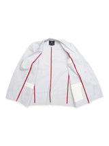 The Gabbiano Riga Blazer by Blue de Gênes features a relaxed fit with red cotton yarn dye stripes lining, white rectangular patches on the lower sides, and a dark interior label. Its shown open in light gray against a white background.