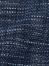 The Kojima Jacket - Navy from Blue de Gênes features a close-up of dark blue woven fabric with a textured pattern, reminiscent of Japanese workwear. It displays a crisscross of dark and light threads, offering a lived-in look with subtle color variations.
