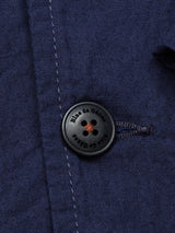 Close-up of the Gervaso Tarlo Blazer - Navy, featuring a black corozo button inscribed with Blue de Gênes. The dark navy blue cotton fabric is elegantly enhanced by visible stitching near the buttonhole.