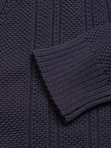 Close-up of the Achille Cardigan - Navy by Blue de Gênes, highlighting its dark knitted ribbed texture on the body and sleeves. The vertical lines paired with a slightly folded sleeve emphasize the texture contrast, showcasing refined knitting techniques.
