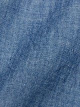 Close-up of the Sandro Chambray Shirt by Blue de Gênes, showcasing its blue chambray fabric with woven texture and subtle shade variations, featuring a diagonal weave pattern characteristic of denim.