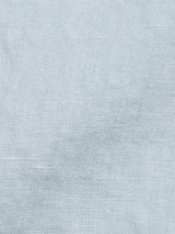 Close-up of the Enrico Beach Shirt in Blue Water by Blue de Gênes, featuring light blue linen with a slightly textured weave, ideal for a breezy summer look. The color is consistent and soft, evoking the gentle appearance of Corozo nut buttons.