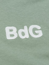 The Salty Logo T-Shirt - Green Bay by Blue de Gênes features a close-up of its green cotton-jersey fabric, showcasing BdG embroidered in white, accentuating the detailed chest embroidery.