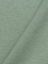 The light green cotton-jersey of the Salty Logo T-Shirt by Blue de Gênes features a soft, smooth texture with a subtle diagonal fold. Its fine weave pattern and gentle color variations are enhanced by lighting, making it an ideal canvas for chest embroidery.