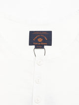 Close-up of the BdG S/S Grandad - Snow White shirt with a round collar and four Corozo nut buttons. A fabric label in the collar reads Blue de Gênes in orange and yellow text, indicating the size as Large.