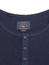 Close-up of the BdG Grandad - Navy henley shirt featuring three corozo nut buttons and a collar tag with gold and brown text displaying Blue de Gênes. Made from cotton slub yarn, this shirt combines timeless style with comfort.