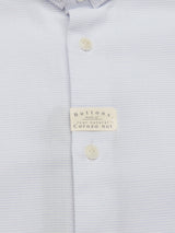 Close-up of the Basso Dob Shirt - Blue Water from Blue de Gênes, featuring a light blue texture with a folded collar and three natural white corozo nut buttons, exemplifying European tailoring elegance. A small label confirms the buttons are genuine corozo nut.