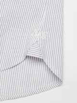 Close-up of the hem of the Basso MC Shirt by Blue de Gênes, featuring navy blue yarn-dye stripes on white seersucker fabric. The initials HC are embroidered near the elegantly curved hem of this regular-fit shirt.