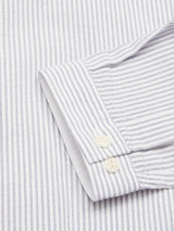 The Basso MC Shirt by Blue de Gênes features a close-up of the white cuff with thin navy stripes and two cream-colored buttons. Made from cotton seersucker, it looks crisp and neatly pressed.
