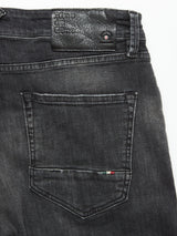 Close-up of the back pocket on Blue de GĂȘnes Vinci G Dark Grey Jeans in grey denim, featuring a leather patch with embossed text and a small stitched red, white, and green detail near the edgeâcrafted in Italy.