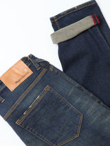 The Repi Dark Vintage Jeans by Blue de Gênes feature a mid blue vintage wash, regular slim fit, cuffed leg with gray and red selvedge edge, comfort stretch denim, and a brown leather brand patch above the back pocket.