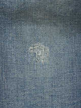 A close-up of Repi Dark Vintage Jeans in mid blue denim by Blue de Gênes, featuring comfort stretch fabric and a central mended patch with textured repair in white and blue threads.