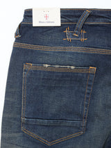 Close-up of the back of Blue de Gênes Repi Dark Vintage Jeans in mid blue denim, featuring orange stitching, pocket, belt loops, and a brand tag with a red and blue shield logo.