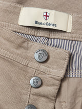 Close-up of BGpaulo Ottawa Trousers - Fungi by Blue de Gênes, featuring beige dobby corduroy, metal shield-embossed buttons, branded label, and striped inner lining.