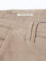 Close-up of Blue de Gênes BGpaulo Ottawa Trousers in Fungi, featuring beige dobby corduroy fabric with a belt loop, front pocket, and a "Made in Italy" fabric label accented by a small Italian flag.
