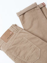 The BGpaulo Ottawa Trousers in fungi by Blue de Gênes are beige dobby corduroy chinos, featuring back pockets, belt loops, a leather brand label with a red and white logo, and slightly rolled cuffs. Made in Italy.