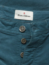 Close-up of BGpaulo Ottawa Trousers in Dark Slate by Blue de Gênes, featuring metallic buttons and a white label with a red cross.
