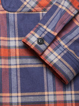 Close-up of the Blue de Gênes Yodo Check Overshirt - Multi Check, showing its relaxed fit, black buttoned cuff, visible stitching, and soft-touch moleskin in blue, orange, and cream plaid.