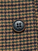 Close-up of a dark button inscribed with Blue de Gênes, sewn onto brown and dark green houndstooth Italian wool fabric of the Massone Check Coat - Multi Check.