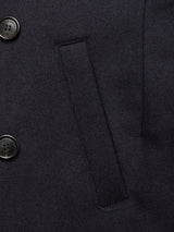Close-up of the Shiba Melton Coat - Dark Navy by Blue de Gênes reveals two black buttons on the left, a central welt pocket, and fine stitching on smooth Italian Melton wool.