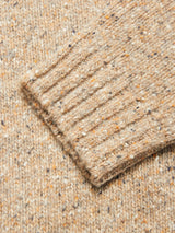 Close-up of the Blue de Gênes Honshu Crewneck Knit - Fungi sleeve, featuring a beige speckled lambswool blend with ribbed cuff and textured flecks of orange, brown, and dark blue on a light background.