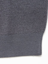 Close-up of the Porto Knit - Dark Slate by Blue de Gênes, featuring textured dark gray 100% wool fabric with a ribbed hem and transition to a waffle pattern, typical in this men's crewneck sweater.