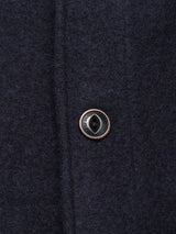Close-up of a black button on the Blue de Gênes Kojima Wool Jacket - Navy, showing detailed stitching and the textured navy boiled wool fabric.