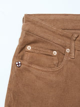 Close-up of Blue de GĂȘnes Vinci Iro Pant in chocolate comfort stretch twill, highlighting the waistband, belt loop, front pocket, and signature pin with a white and red cross shieldâperfect for regular fit jeans enthusiasts.