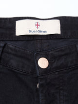 Close-up of the waistband of Vinci Iro Pant - Navy by Blue de GĂȘnes, showing a label with a red and white shield logo and a metal button embossed with a crest. Made from comfort stretch twill for lasting comfort.