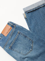 Two pairs of Blue de Gênes Marco Used Jeans - Used are laid flat; one displays the back pocket with a brown leather patch, the other is folded to reveal the cuff and 100% cotton denim texture.