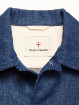 Close-up of the Yuma Fano Jacket - Denim Blue by Blue de Gênes, showing its workwear-inspired collar and an inner beige label with the Blue de Gênes name and a red and white shield logo above it.