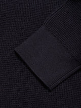 Close-up of the Otia L/S Polo Knit by Blue de Gênes in navy, showing its dark, textured cashmere blend with a ribbed cuff overlapping a waffle-knit pattern.