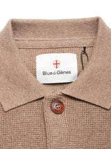 Close-up of a beige textured collared shirt with a brown button and Blue de Gênes label, stylishly paired with the Gifu Knit Cardigan - Chocolate by Blue de Gênes.