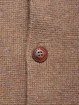 Close-up of the chocolate brown textured fabric from the Gifu Knit Cardigan by Blue de Gênes, featuring a single engraved button and dark thread. This wool blend piece showcases the cardigan’s quality craftsmanship in every detail.
