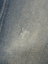 A close-up of Blue de Gênes Vinci Dark Vintage Jeans in mid blue denim highlights a discreet, faded patch repaired with lighter thread, seamlessly blending into the fabric.