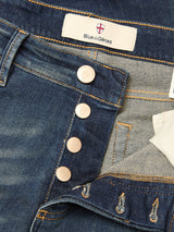 Close-up of Vinci Dark Vintage Jeans by Blue de Gênes in mid blue denim, showing four crest-engraved metallic buttons, the Blue de Gênes inner label, and visible inside pocket with stitching details.