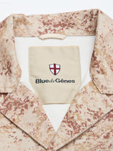 Close-up of the BGkendrick Print Jacket by Blue de Gênes, showing its beige and brown patterned cotton twill collar, an inner “Blue de Gênes” label, and a small shield logo with a red cross on white.