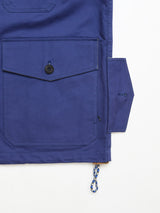 A close-up of the Blue de Gênes BGcanopy Jacket in Navy Peony, showcasing heavy cotton fabric, a large buttoned pocket, angular flap with buttonhole, and a blue-and-white braided drawstring—a nod to classic workwear heritage.