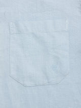 A close-up of the Blue de Gênes BGenric Hope L/S Shirt in Blue Fog shows a light gray pocket with a small shield emblem stitched on the corner, ideal as a breathable summer shirt.