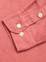A close-up of the BGenric Hope L/S Shirt - Coral by Blue de Gênes shows its textured, breathable linen cuff with two white buttons laid flat on a matching coral background.