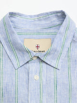 A close-up of the BGenrico Mida Shirt by Blue de Gênes, featuring blue and green stripes, a cut away collar, white buttons, and a beige brand label with a red cross and “de Gênes” inside the collar.