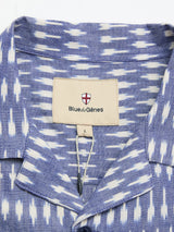 Close-up of the BGforma Onda S/S Shirt by Blue de Gênes in a blue pattern. Features a beige label with a red and white shield above the brand name. This oversized, 100% cotton resort shirt is size L.