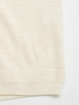 Close-up of the roll-rib hem on the BGmonty Knit - Chalk crewneck by Blue de Gênes, made from a cream cotton-linen blend and featuring a subtle embroidered shield with a cross near the edge.