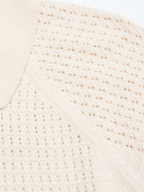 Close-up of the BGbilly S/S Cardigan in Chalk by Blue de Gênes, featuring a cream hue, textured vintage knit, ribbed collar, and a pattern of small, evenly spaced holes.