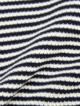 Close-up of the BGbob Knit Polo - Navy by Blue de Gênes, featuring cotton knit fabric with horizontal black and white stripes. Gentle waves and shadows highlight its classic nautical style.