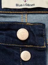 Close-up of Blue de Gênes Vinci Pala Dark V2 Jeans in dark blue denim with two branded metallic buttons, shield emblem, yellow stitching, and a “Blue de Gênes” label—crafted from comfort stretch denim and made in Italy.