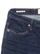 A close-up of the Repi Dai V Dark V2 Jeans in dark blue denim by Blue de Gênes shows the front pocket, belt loop, and badge with a red and white cross. A Made in Italy label is visible inside the waistband.