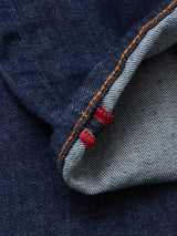 Close-up of durable dark blue denim on the Blue de Gênes Repi Dai V Dark V2 Jeans, featuring a rolled edge, orange stitching, and two red bar tacks highlighting classic five-pocket selvedge detail.