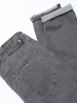 A pair of folded Blue de Gênes BGrepi Giulio Light V2 Jeans in grey denim is shown on a white surface, featuring the back pocket, black brand label, and grey inner cuff lining.